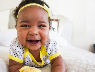 A smiling baby laying on its front