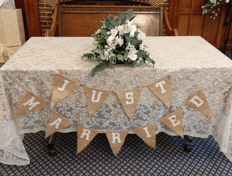 Wedding table with flowers, a table cloth and a banner saying just married